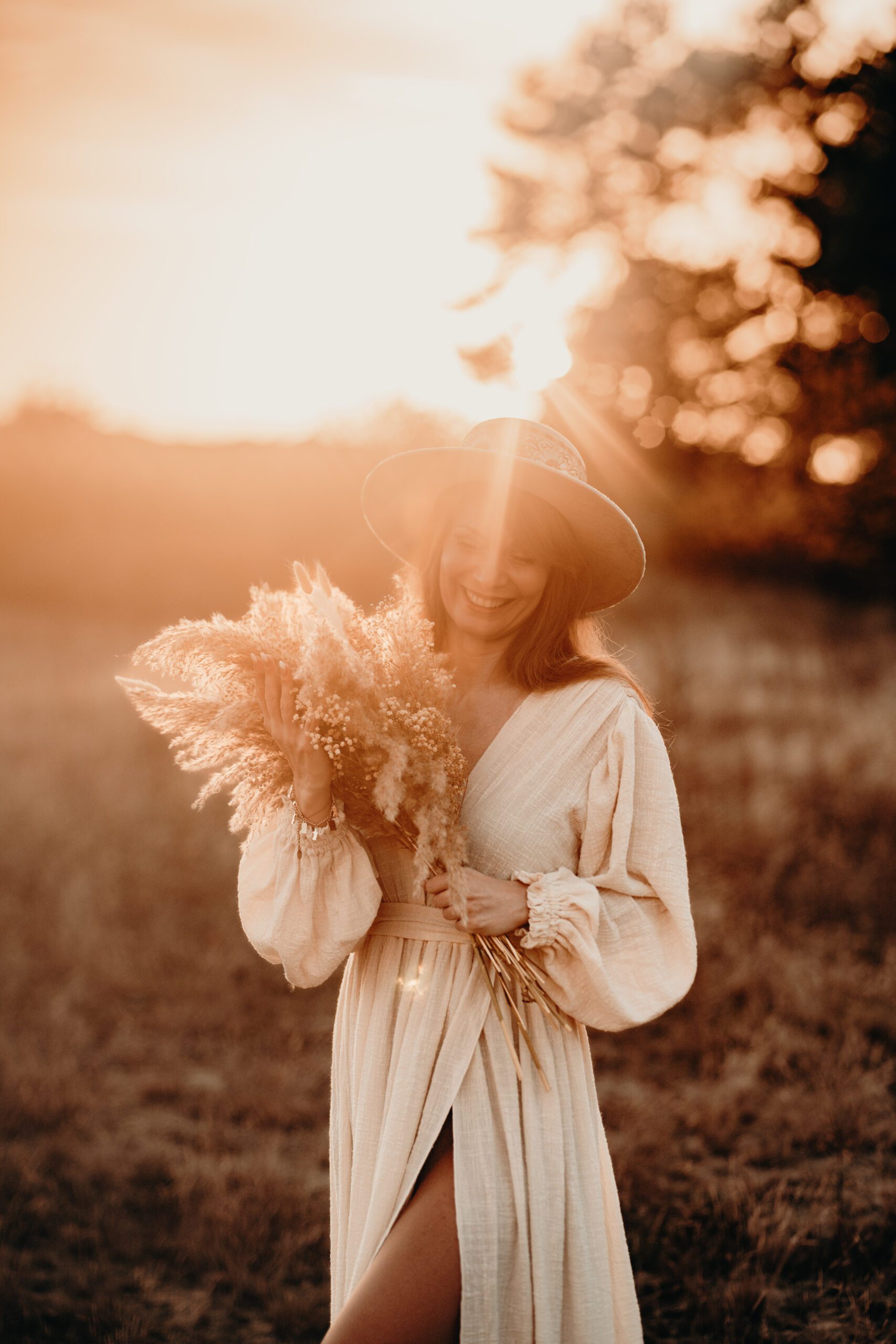 Frau mit Hut im Boho-Kleid im Sonnenuntergang